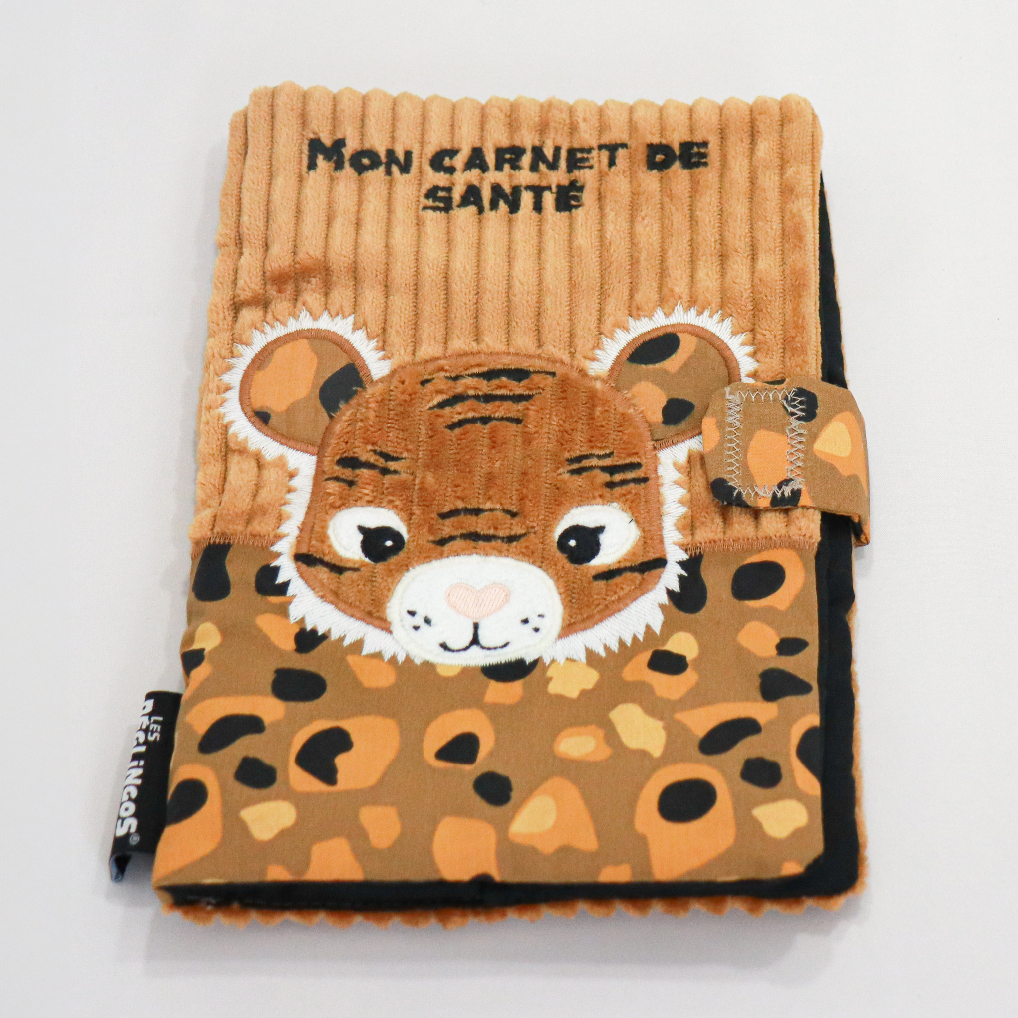 Protège carnet de santé pour bébé Déglingos, modèle tigre. Housse en tissu côtelé marron avec tête de tigre en relief, broderies blanches et noires. Poche à motifs léopard multicolores (noir, beige, orange) et fermeture velcro. Inscription "Mon carnet de santé" brodée en noir sur le dessus. Accessoire doux, original et ludique pour enfant, conforme aux normes CE.