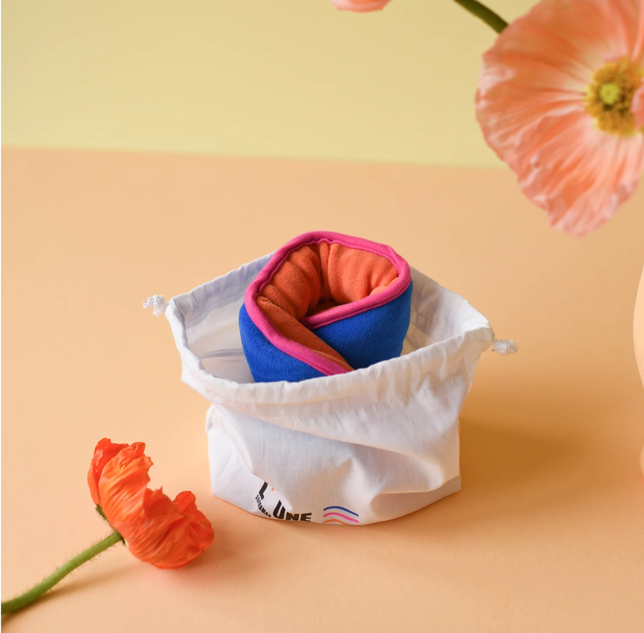 Bouillotte de règles couleurs flashy orange et bleu marine avec bordure rose et son sachet de rangement