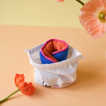 Bouillotte de règles couleurs flashy orange et bleu marine avec bordure rose et son sachet de rangement