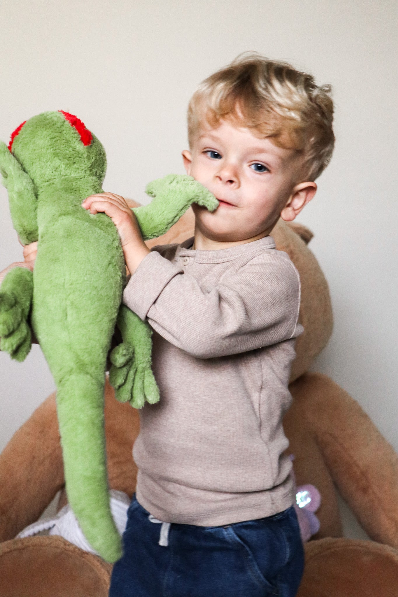 Petit garçon qui joue avec une peluche bouillotte gecko dans les mains 