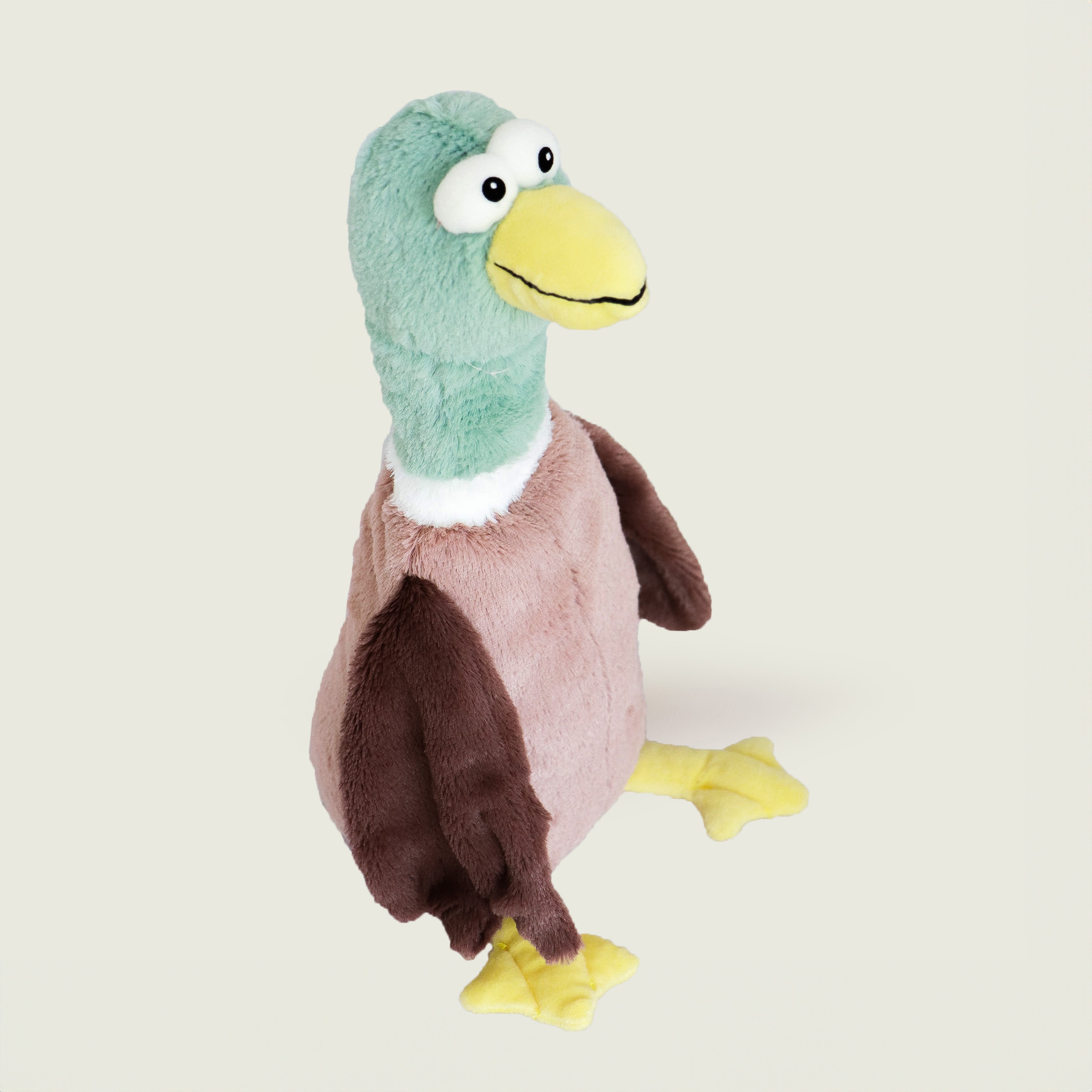 Bouillotte peluche en forme de canard de la marque Warmies, vu de profil, avec une tête verte, un bec jaune et un corps marron 