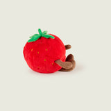Bouillotte peluche en forme de fraise, rouge avec sur le haut deux feuille et une tige verte. Elle a un visage avec un sourire, des bras et des jambes marron. Elle est de profil