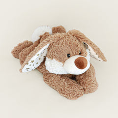 Bouillotte peluche lapin, marron et blanc avec des étoiles dorées dans les oreilles. Il est en position allongée 