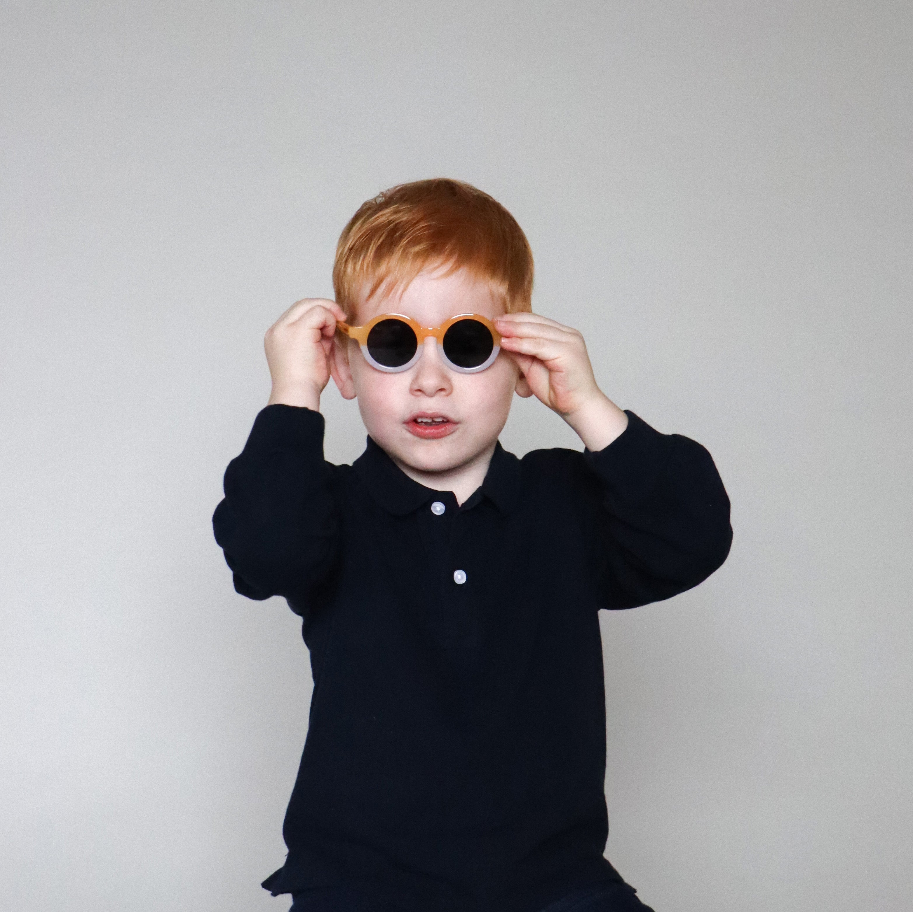 Paire de lunettes de soleil bébé catégorie 4, bicolore moutarde et blanc avec monture en TPEE effet transparent. Mise en situation portée avec vue rapprochée