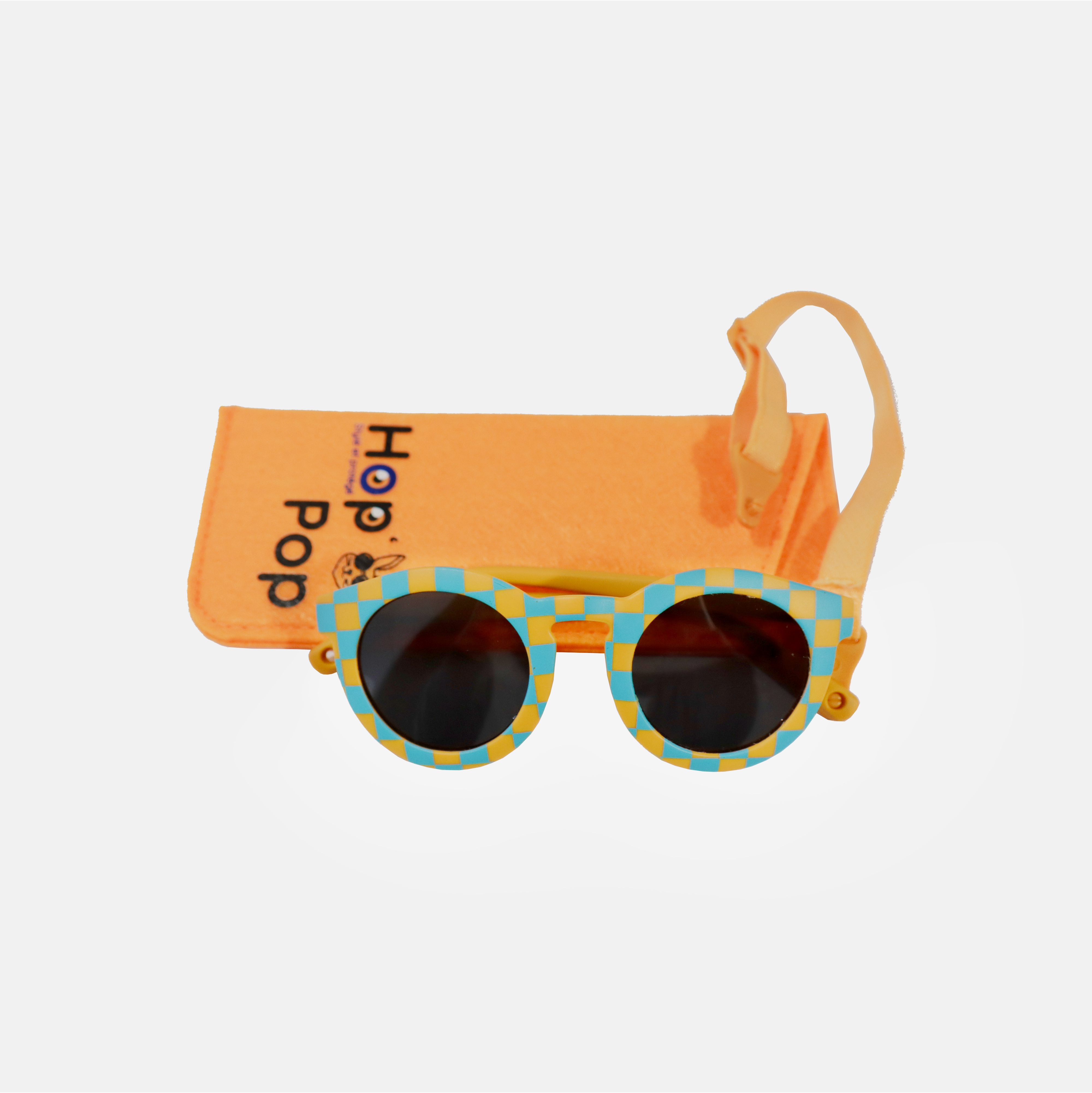 Lunette de soleil pour enfant à monture ronde motif vichy bleu et jaune et son cordon, posée devant leur étui de rangement en feutrine orange marqué "Hop'Pop".