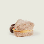 Peluche bouillotte Sandwich personnifié avec visage souriant, bras et jambes: deux tranches de pain marron garnies de fromage jaune, tomates rouges et salade verte. Vue de profil