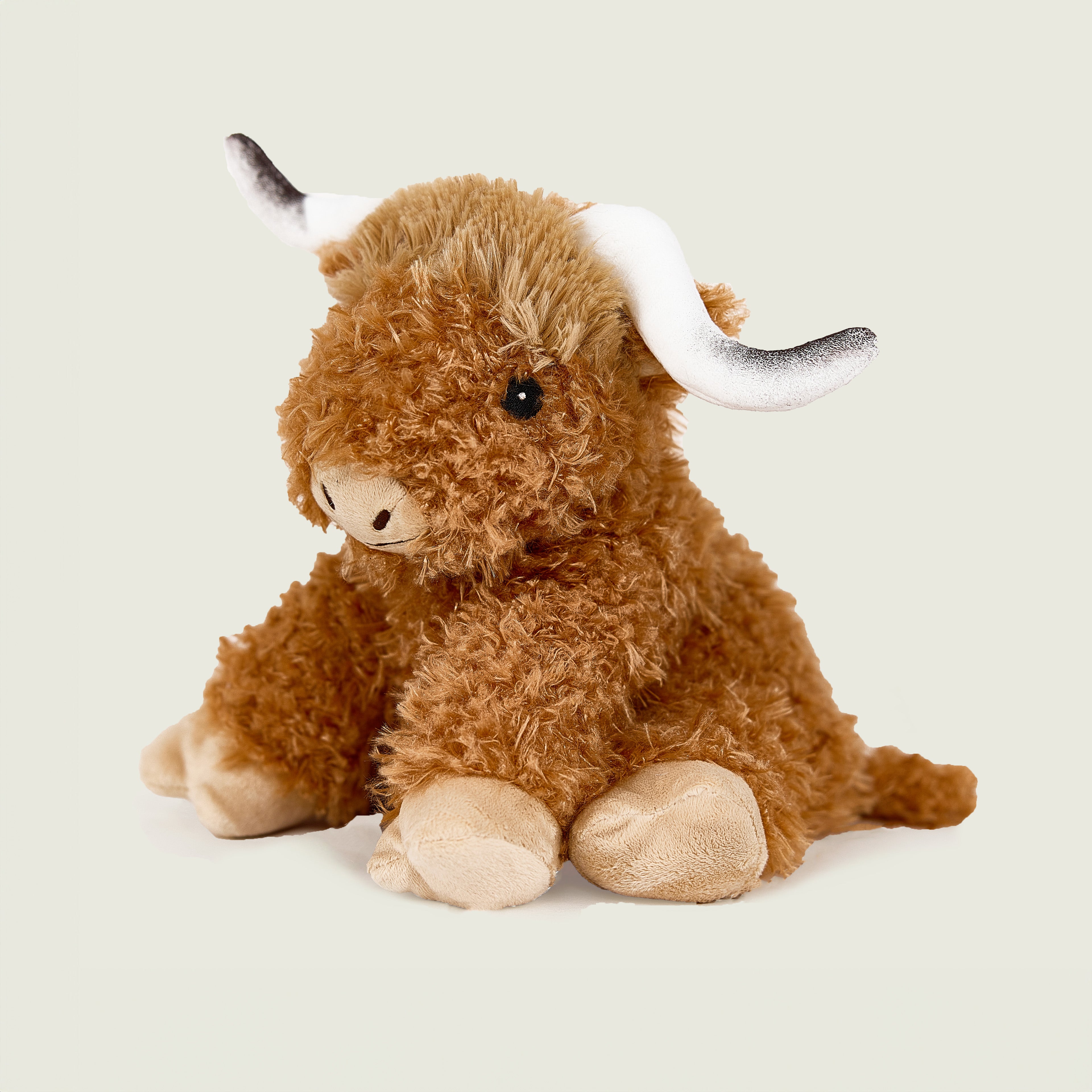 Peluche bouillotte déhoussable Vache Highland, marron à poils bouclés avec cornes blanches et noires. Vue de profil
