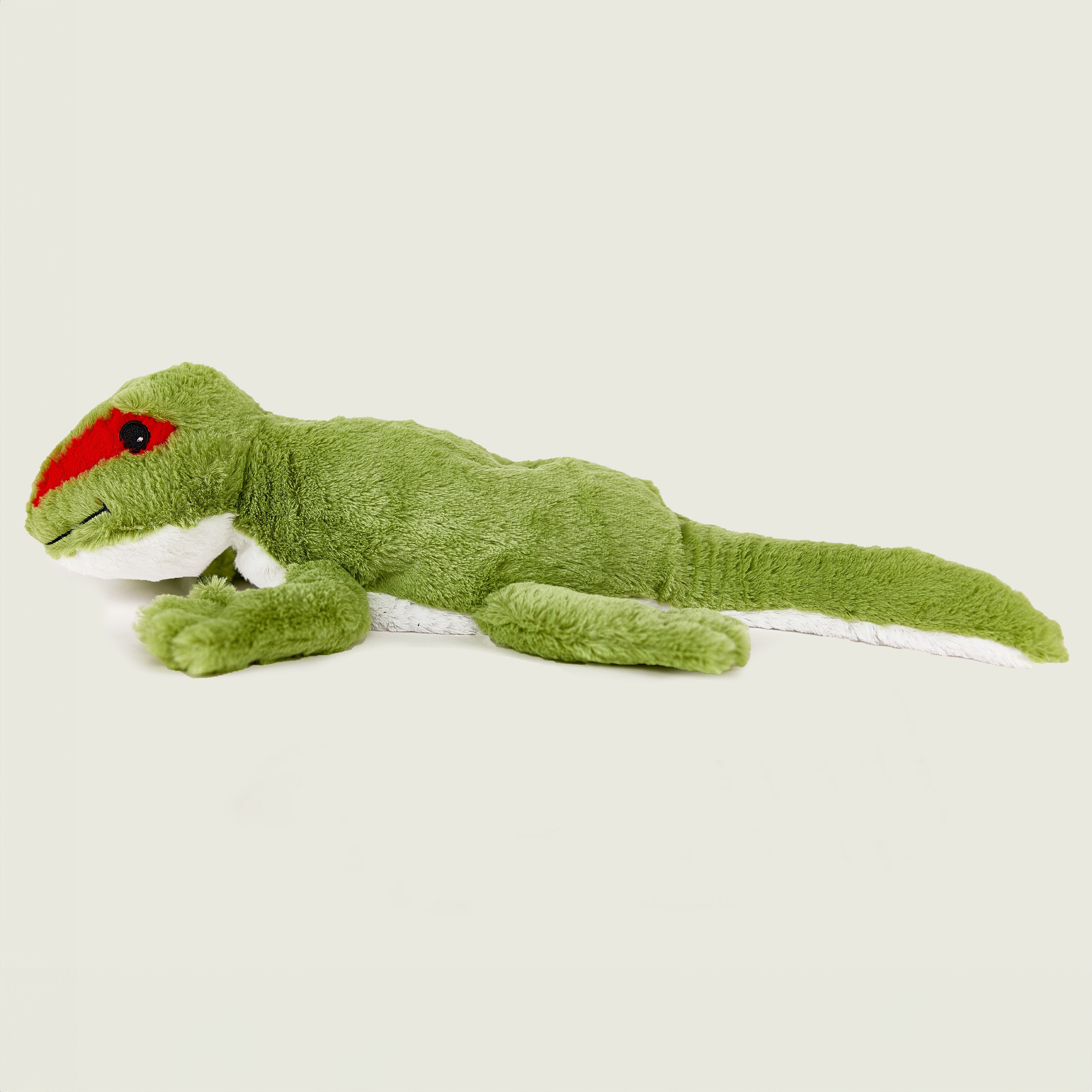 Peluche bouillotte déhoussable gecko verte, corps inférieur blanc, avec visage souriant et aplats rouge au niveau des yeux. Vue latérale