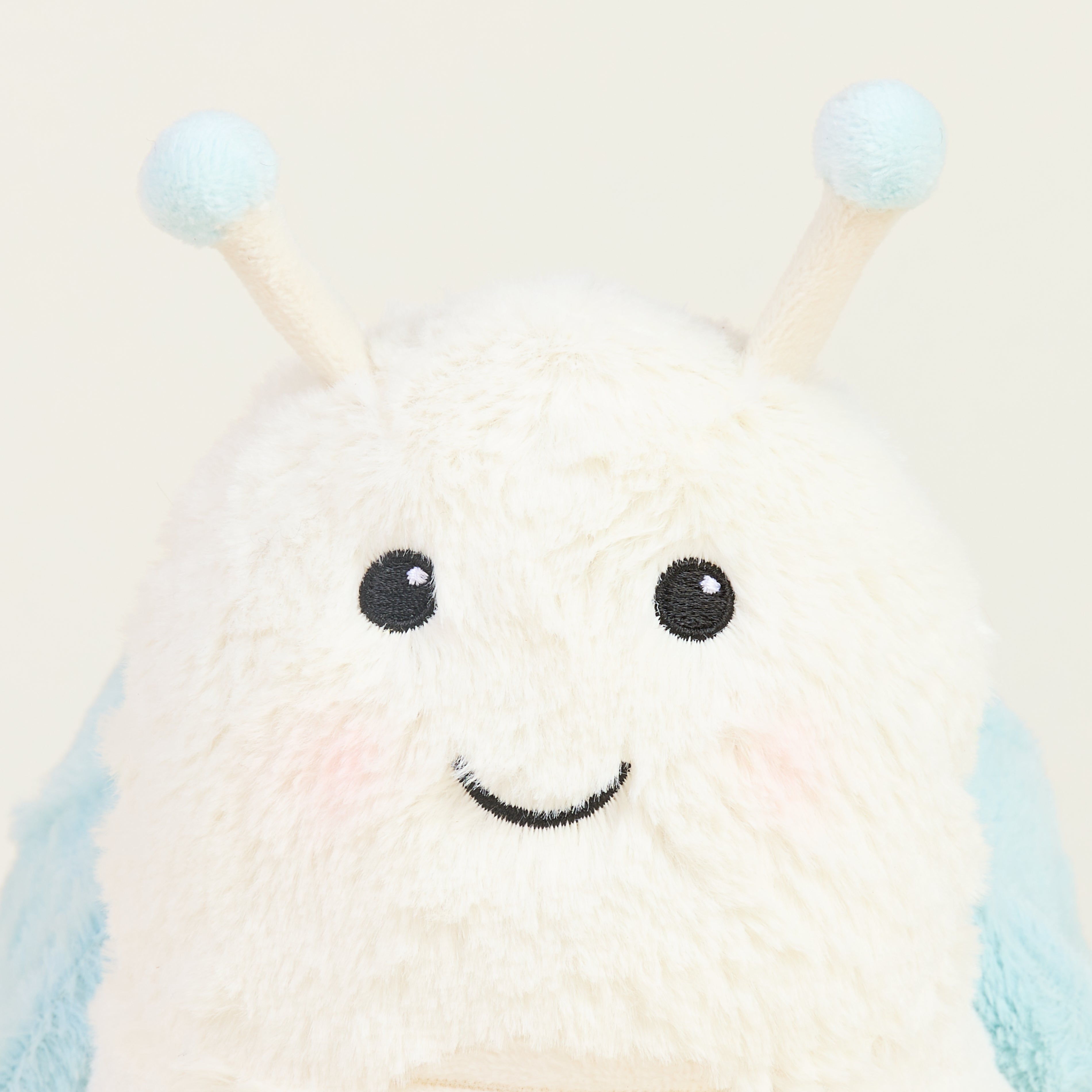 Peluche bouillotte escargot, blanc et bleu pastel, avec antennes , gros plan sur visage souriant
