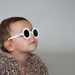 Paire de lunettes de soleil bébé catégorie 4, monture en TPEE blanc en forme de fleur. Mise en situation portée de profil