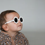 Paire de lunettes de soleil bébé catégorie 4, monture en TPEE blanc en forme de fleur. Mise en situation portée de profil