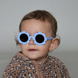 Paire de lunettes de soleil bébé catégorie 4, monture en TPEE bleue en forme de fleur. Mise en situation portée de profil