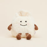 Peluche bouillotte Ravioli personnifié, crème et marron, avec visage souriant, bras et jambes. Vue de face 
